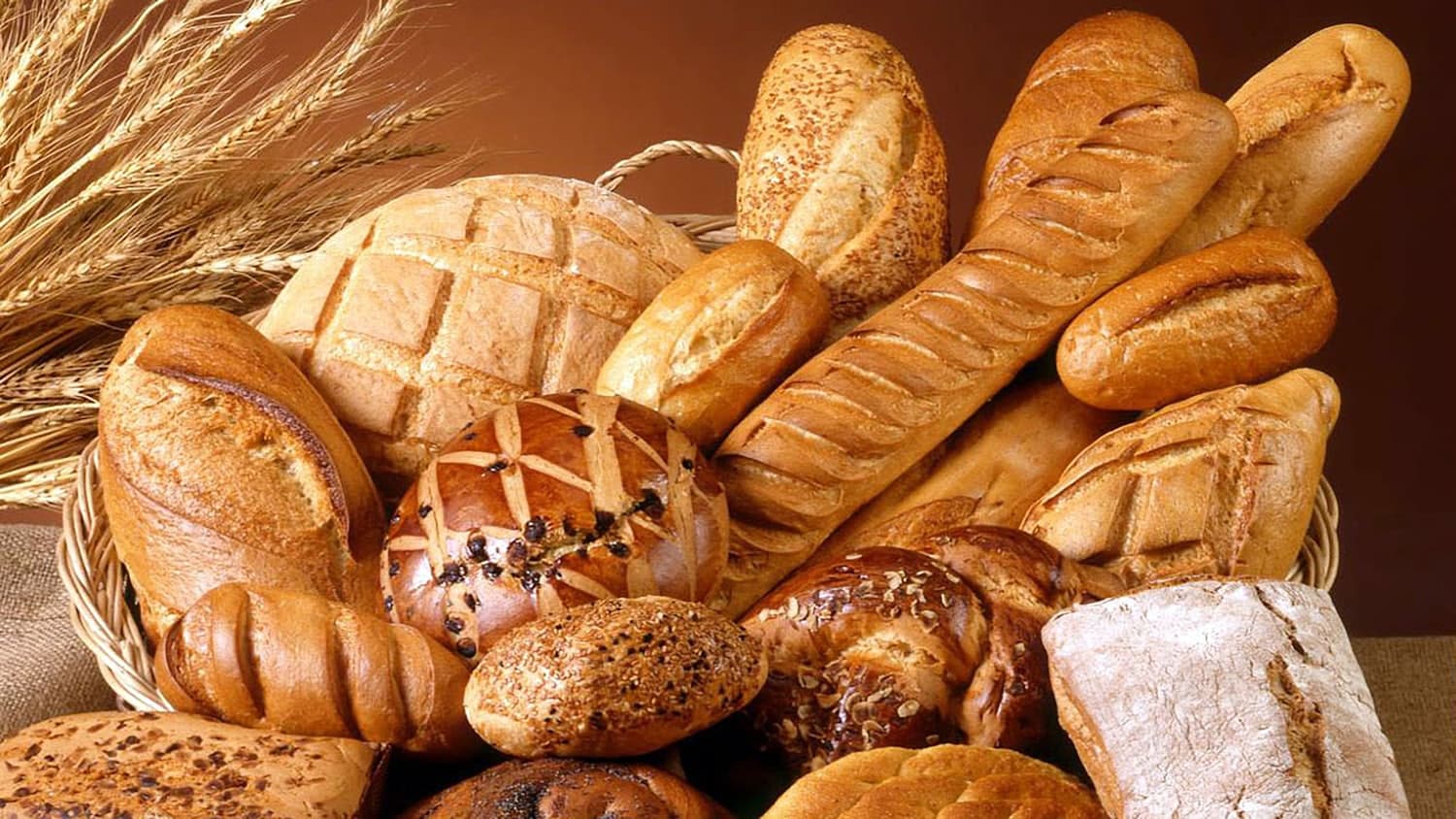 A baker pulling loaves from a hot oven